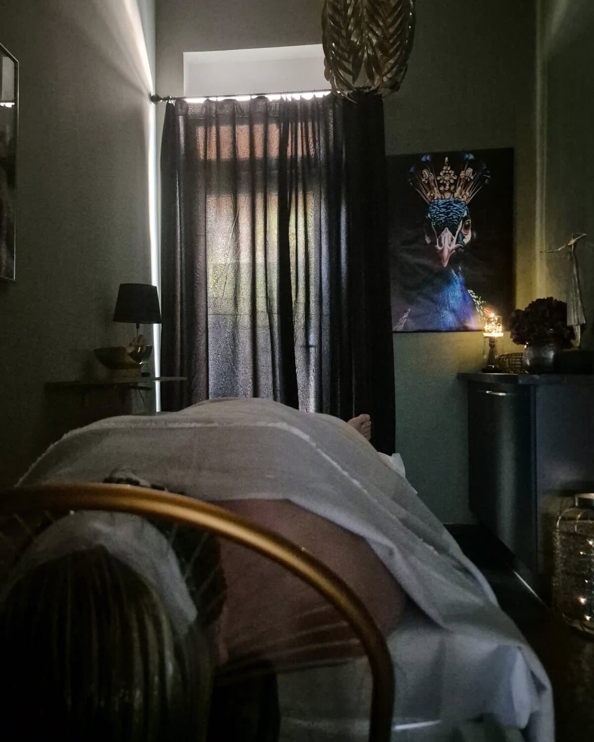 Behandlungsraum von Headspa Nova im Lampenlicht, ein Gast liegt zugedeckt auf der Liege