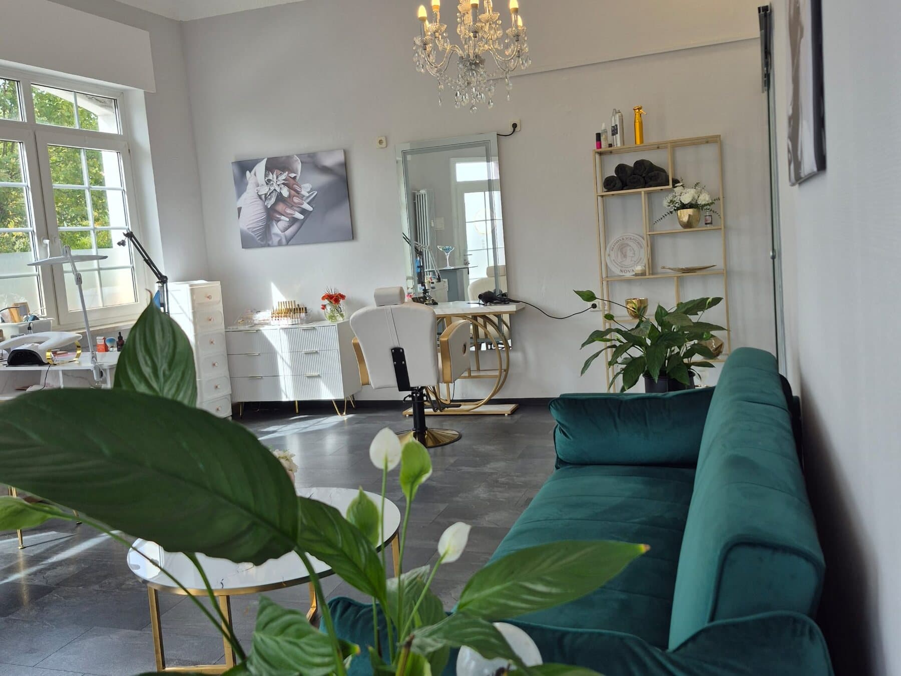 Heller Raum von Headspa Nova mit Kronleuchter, grünem Samtsofa, goldenem Regal und dem Nova-Logo im Regal